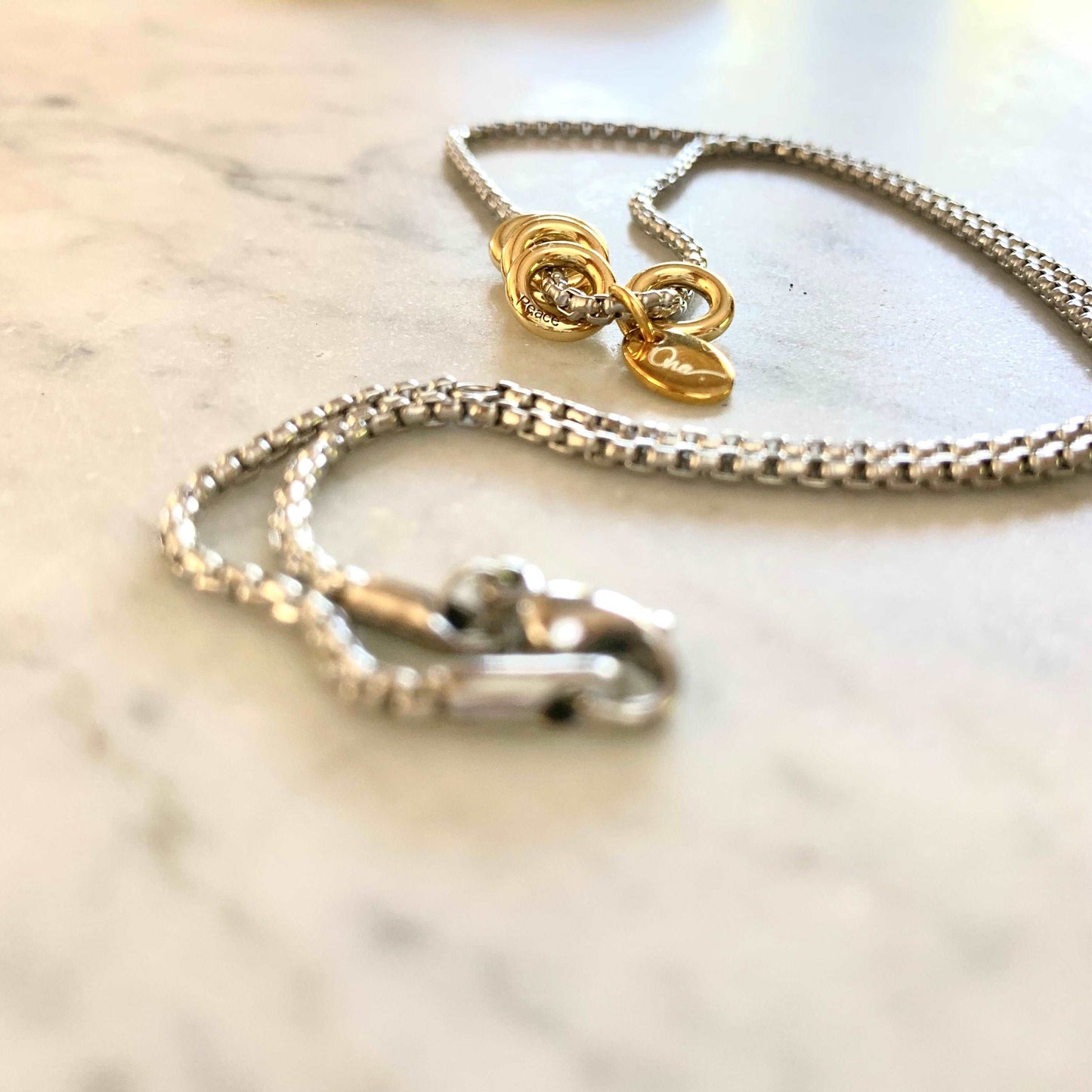 Khai Necklace - Steel box chain with 925 Silver Rings Vermeil plated in 18K gold on marble table