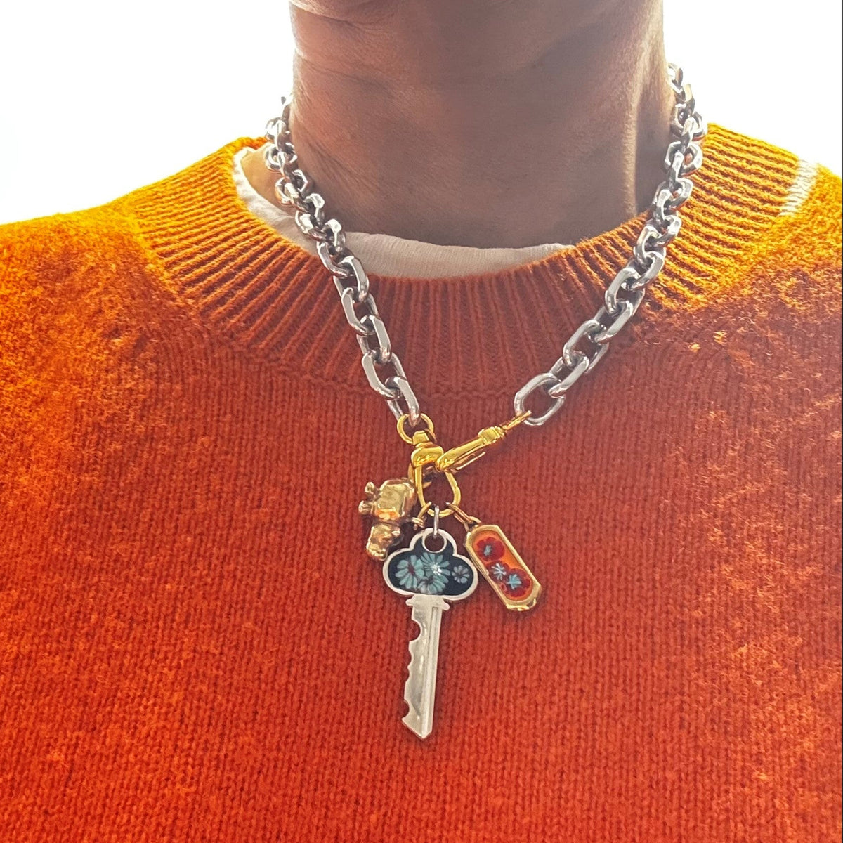 orange sweater showing charms stacked on riley chains - rhodium with gold clasp
