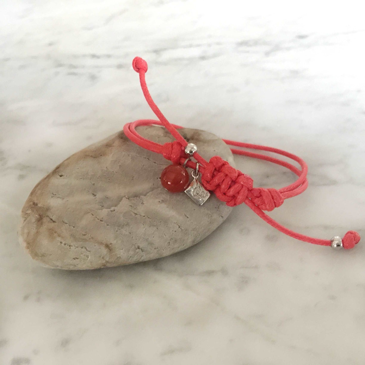 Red strings of destiny bracelets With Red Carnelian Bracelet on rock