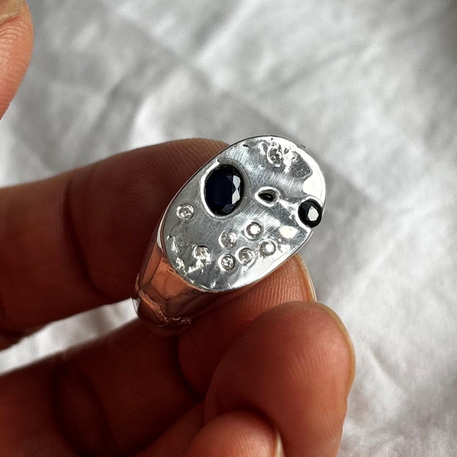 joni oval sand cast ring with blue and black sapphires and white flush set sapphires