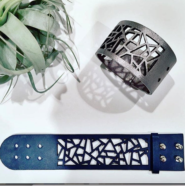 Margaret Leather Laser Cut Bracelet open flat and buttoned on white background next to succulent. 