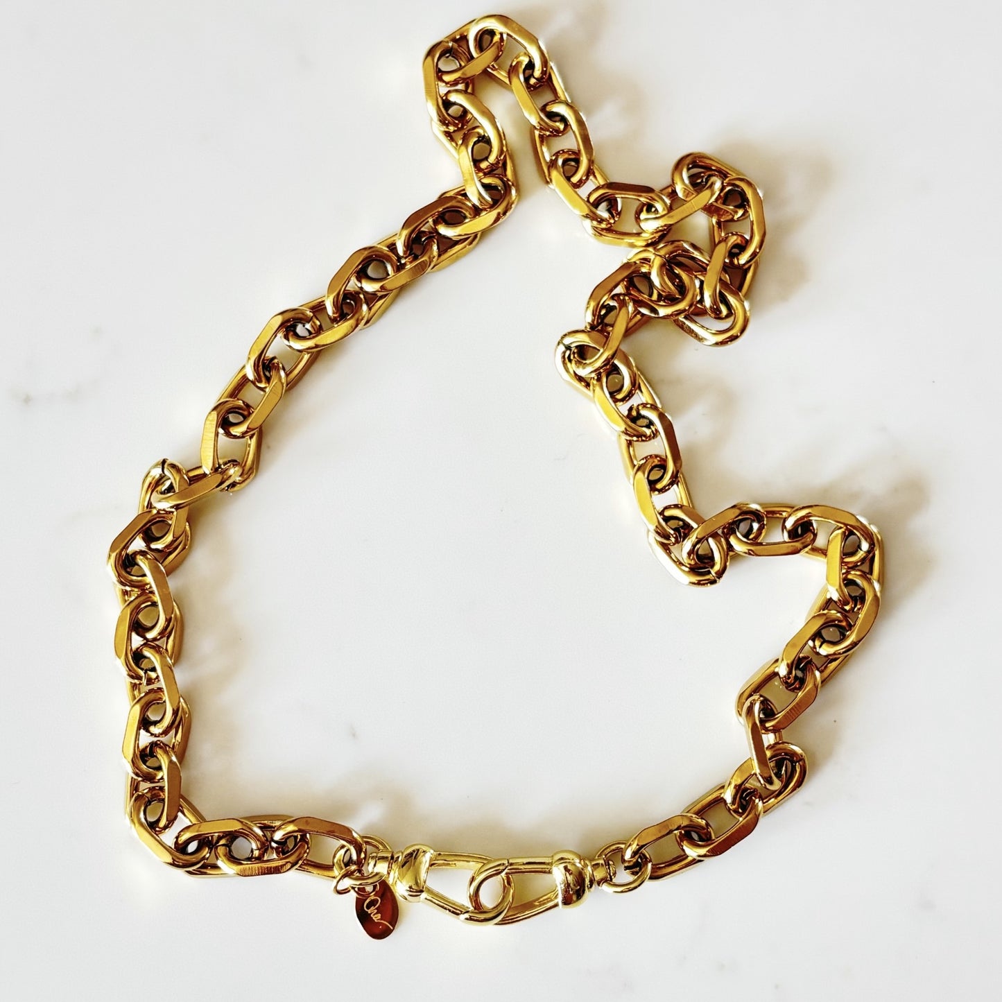 Riely chunky 18K plated gold chain necklace with a 18K plate push clasp, laid out on a white marble surface.