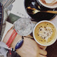 top view of table and coffee - woman wearing corded blue quartz Bracelet and  String Of Destiny With Red Carnelian