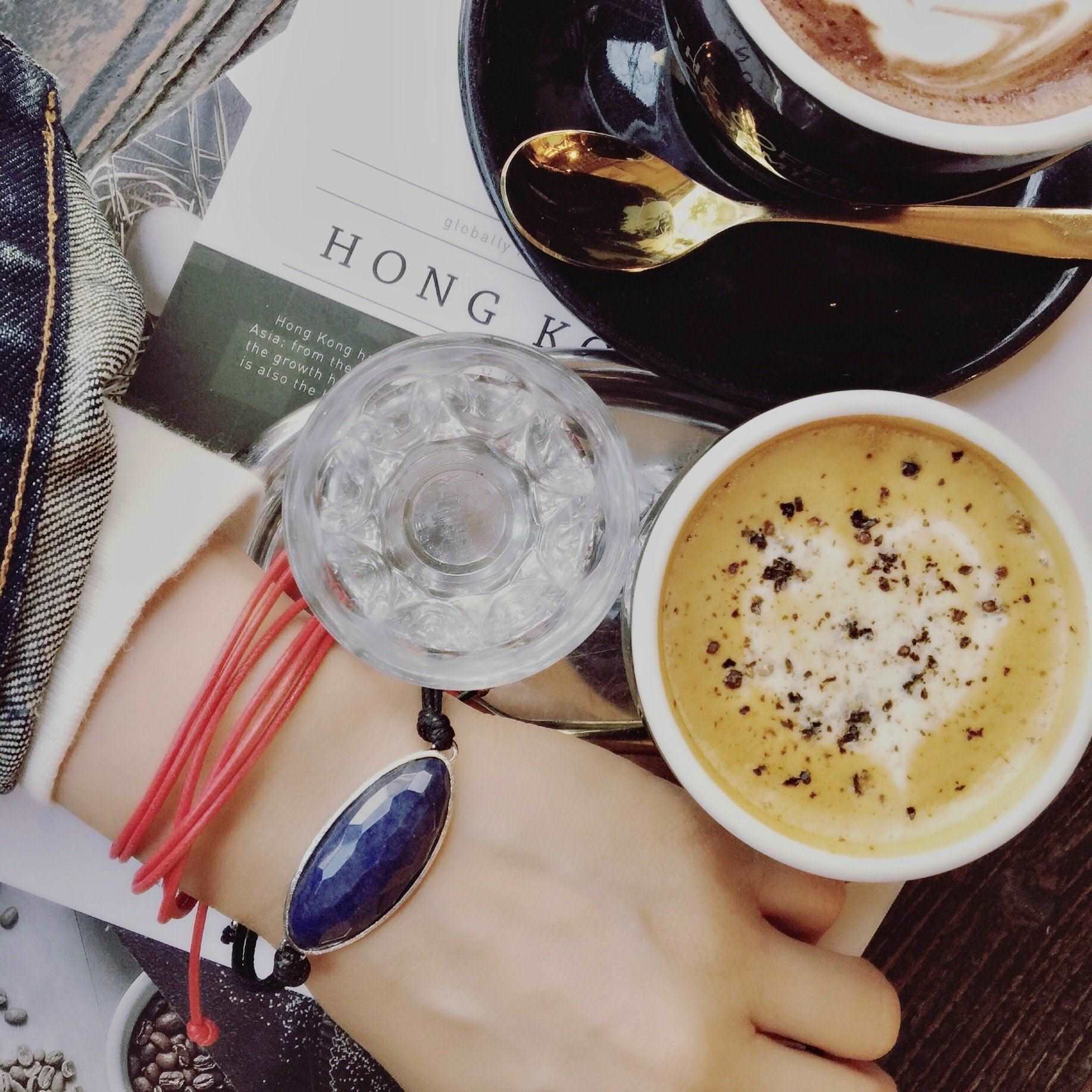 top view of table and coffee - woman wearing corded blue quartz Bracelet and  String Of Destiny With Red Carnelian