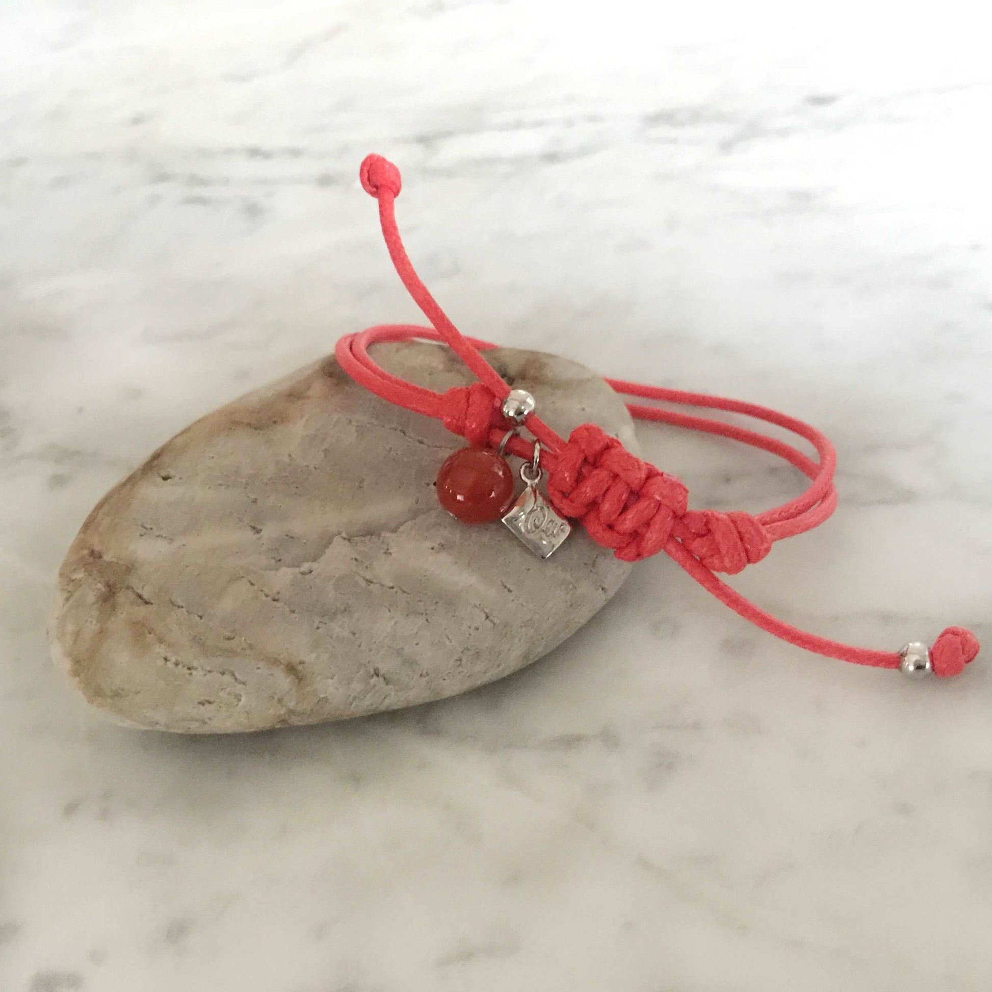 Red strings of destiny bracelets With Red Carnelian Bracelet on rock