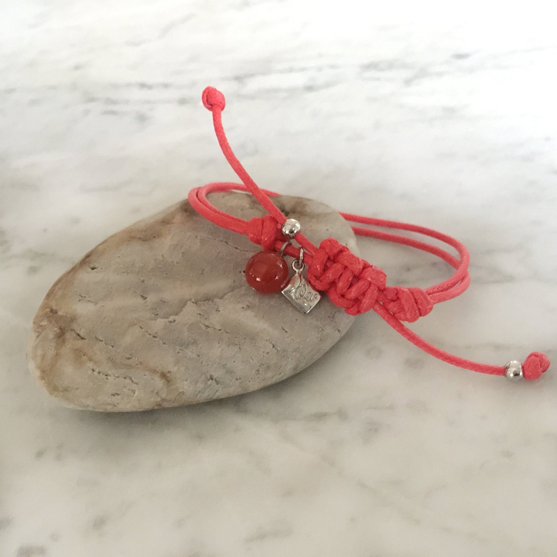 Red strings of destiny bracelets With Red Carnelian Bracelet on rock