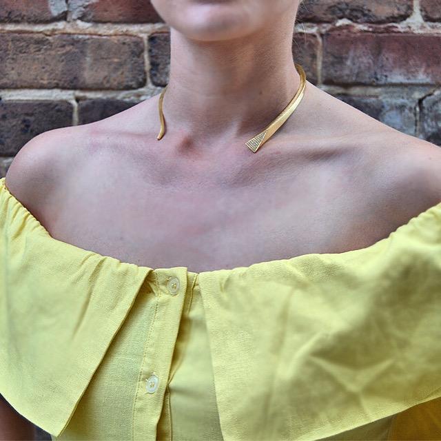 Taylor Stone of Stone Files wearing bright yellow off shoulder dress with Mantra Small Dagger Collar