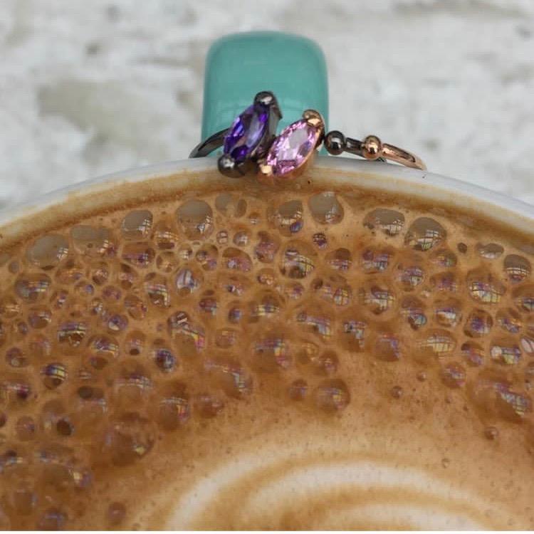 Two Little Jewels - Marquise Cut Open Ring With Swarovski Crystals sitting on a rim of a latte