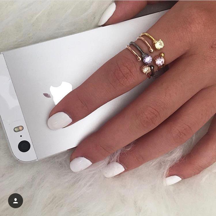woman with white manicure holding silver iPhone wearing 4 Little Jewels - Round Cut Open Ring With Swarovski Crystals stacked