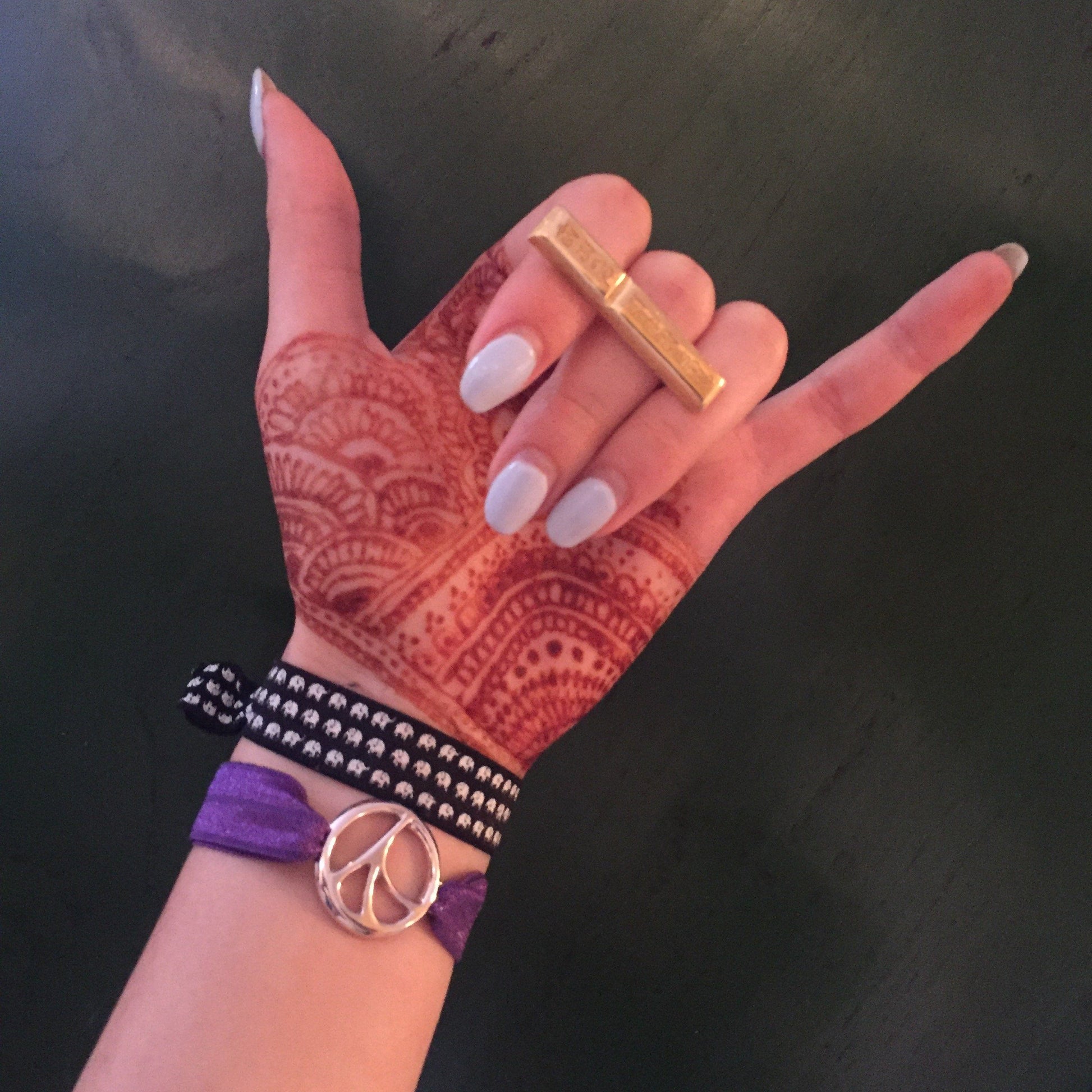 Hang Loose sign with henna and elastic bracelets wearing Mantra Long Knuckle Ring With Edge