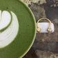 Mantra Open Cube Ring With Swarovski Crystals sitting on a white mug 